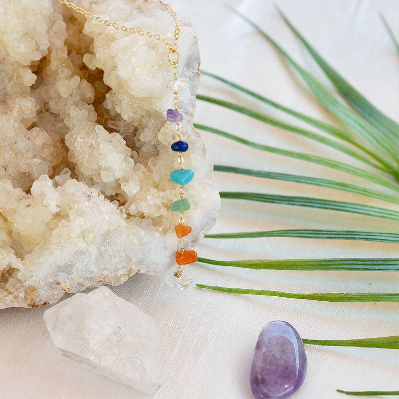 Healing Chakra Necklace with raw gemstones placed on a crystal cluster, highlighting vibrant stones for each of the 7 chakras.