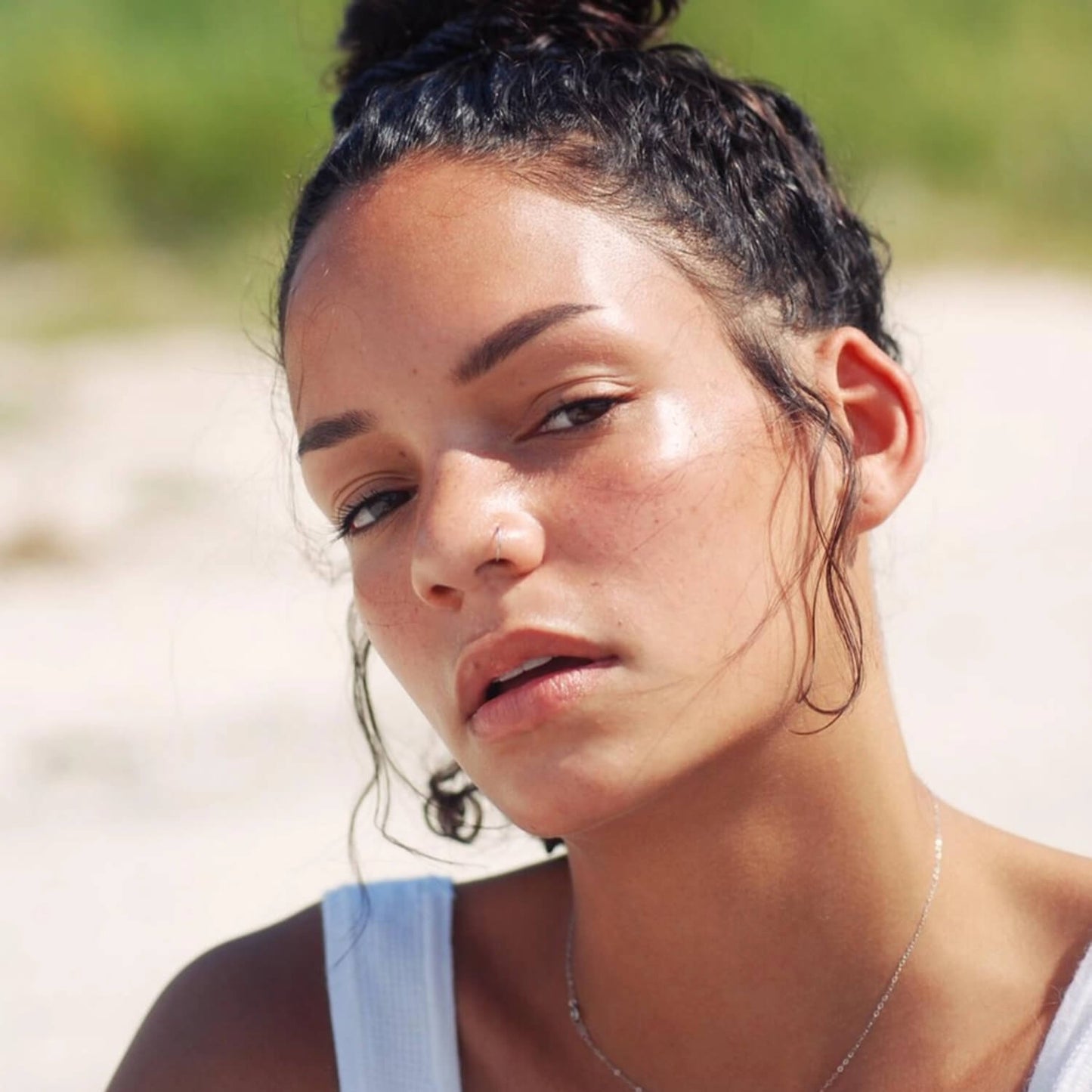 a woman with tan skin with rose quartz highlighter stuck applied to her cheekbones