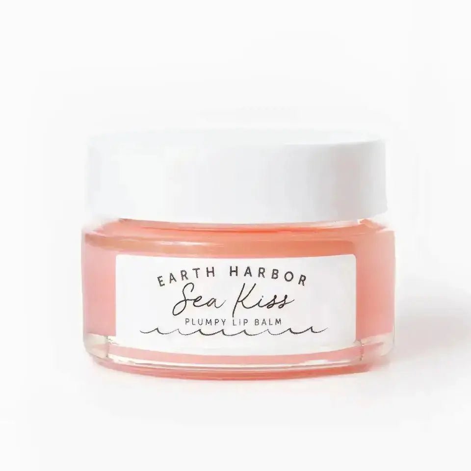 Earth Harbor Naturals SEA KISS organic lip plumping balm in a glass jar with a white lid, featuring a soft pink hue for hydration and smooth lips.