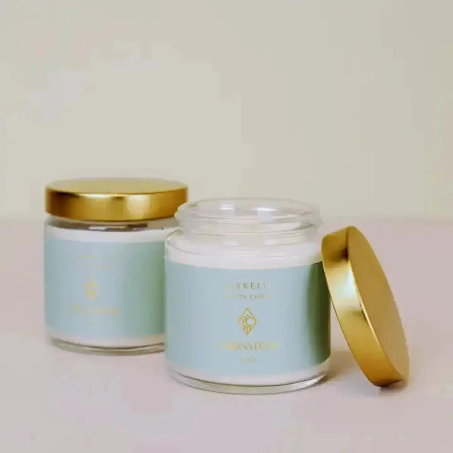 two jars of Jax Kelly candles sitting next to each other