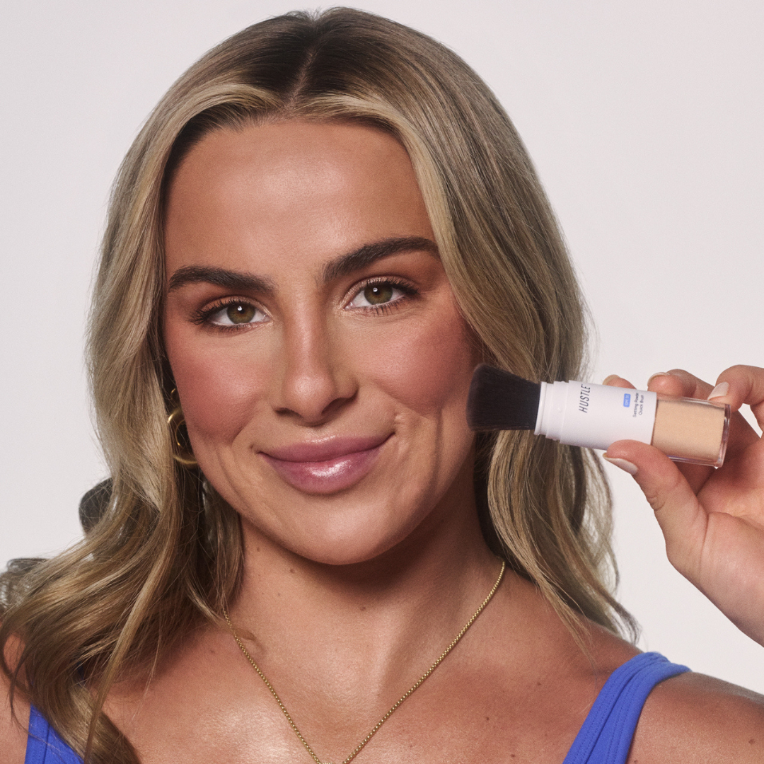 Cavinder sister applying SPF powder with a brush and bottle against a plain background