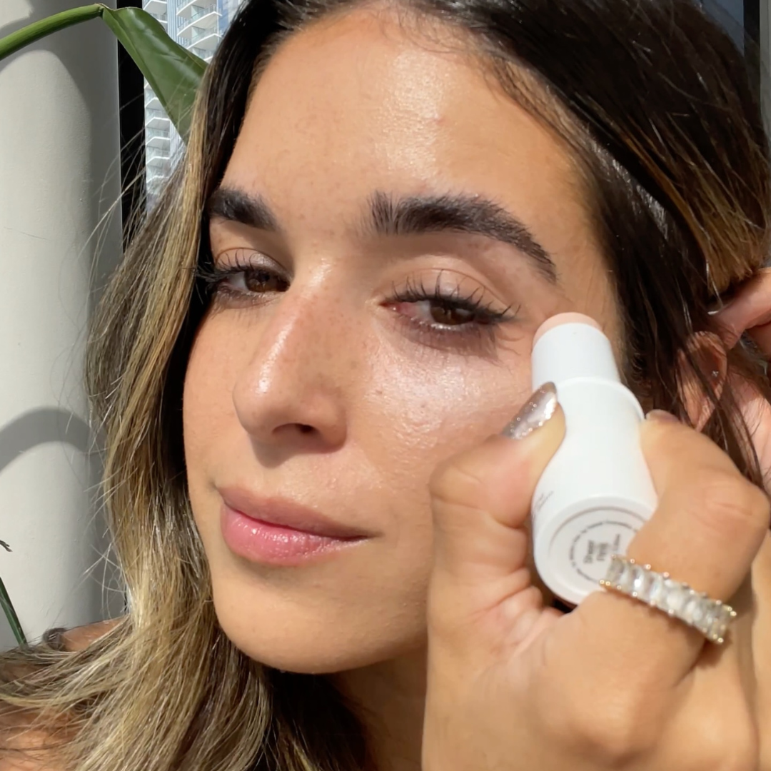 Woman applying color correcting balm to her eye area