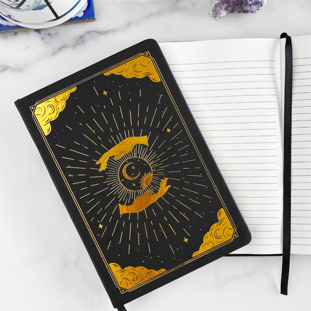 Black notebook for mindfulness journey with gold celestial design on a white surface