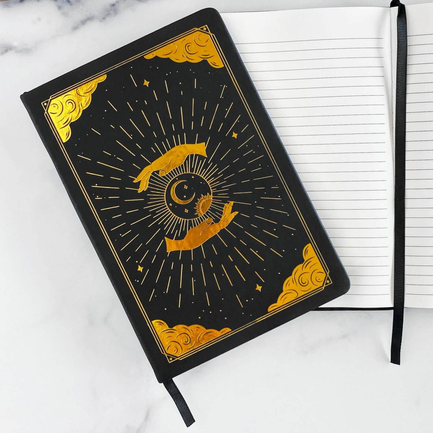 Black intention and mindfulness journal and notebook with gold celestial design on a white marble surface