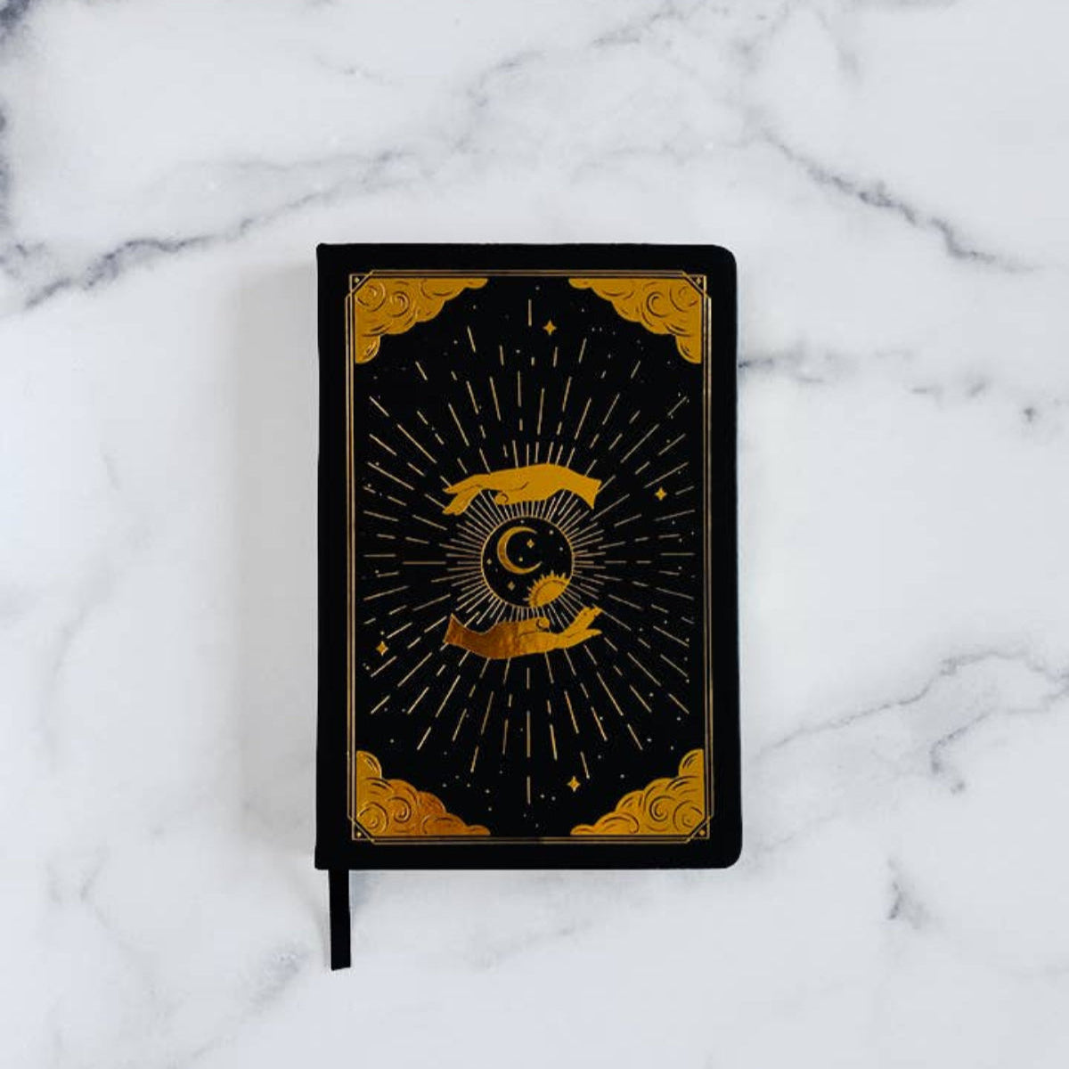 Black notebook with gold design for intention and mindfulness on a marble surface