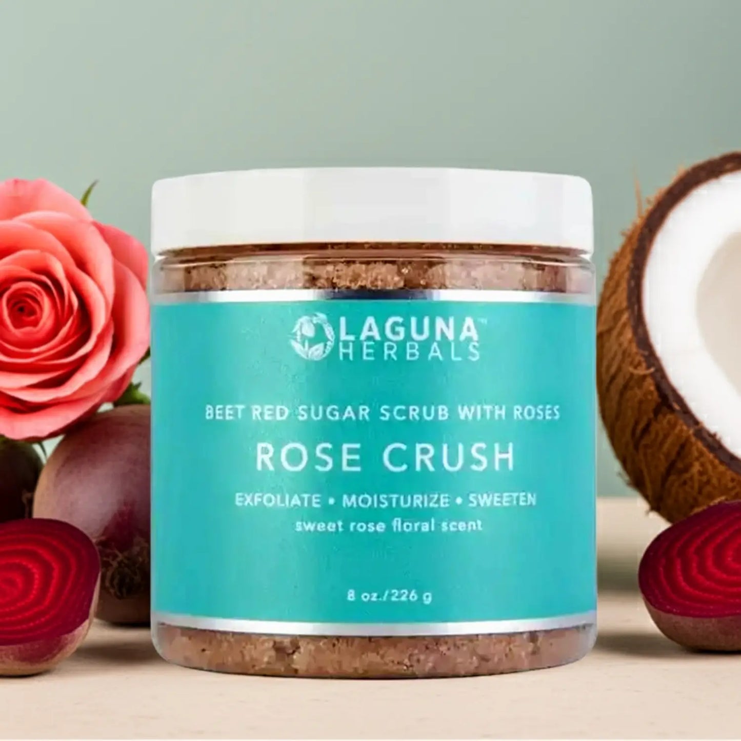Jar of Laguna Herbals Rose Crush scrub with roses and a coconut on a light background