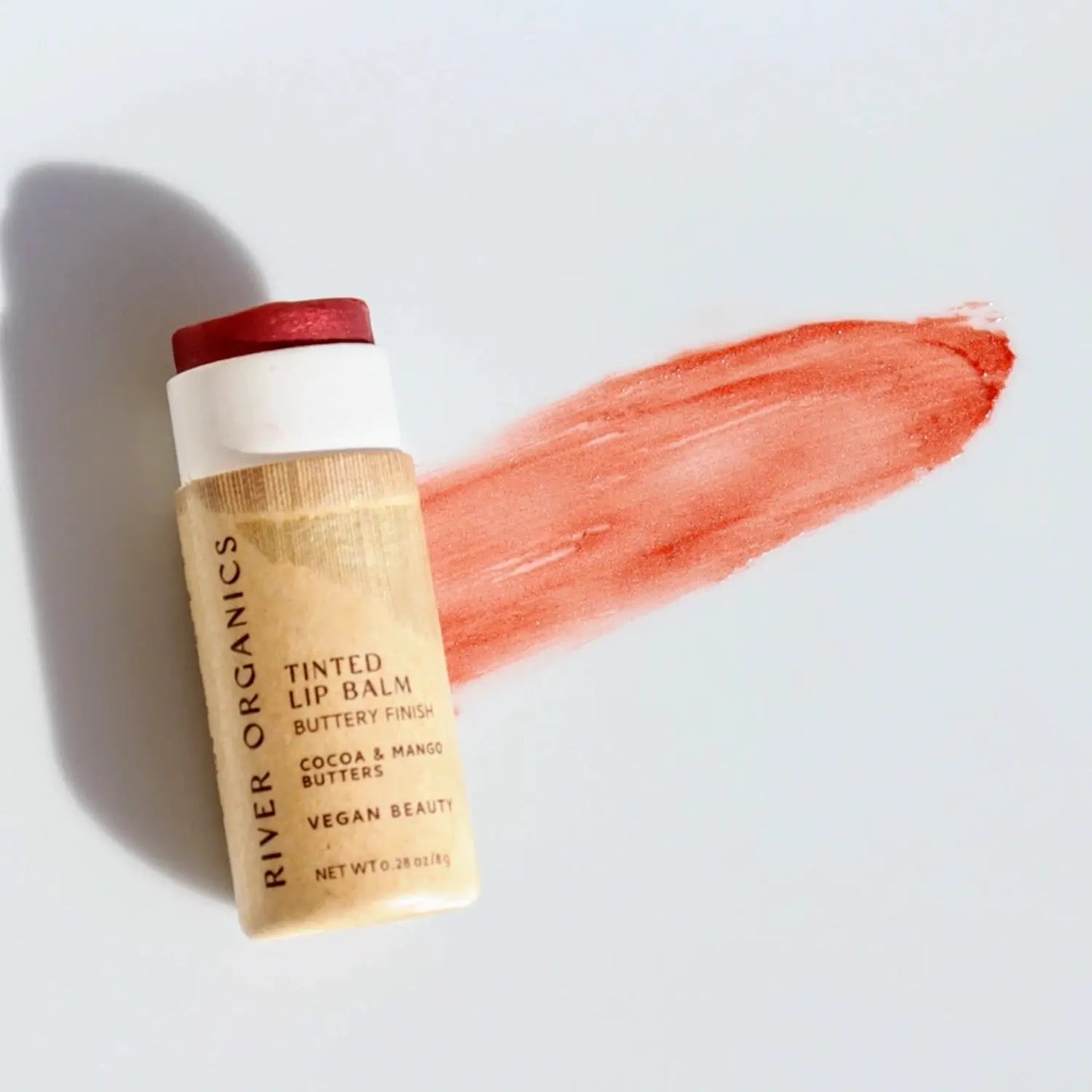 Tinted lip balm with a swatch of red color on a light background