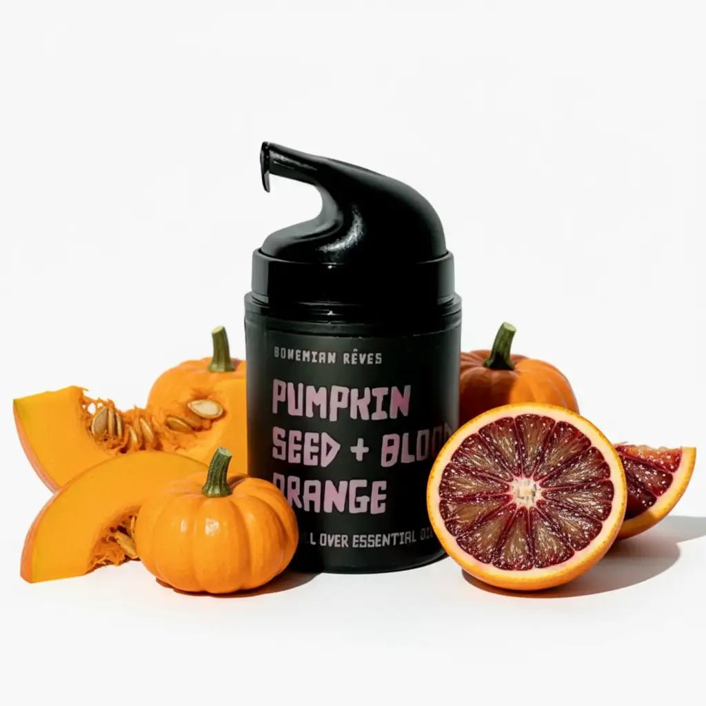 Black pump lotion bottle with pumpkin seed and blood orange text, surrounded by pumpkins and an orange on a white background.