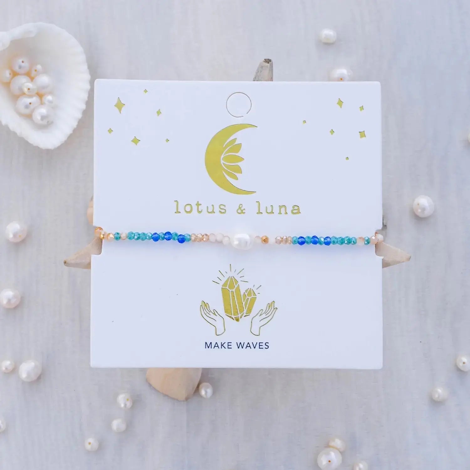 Lotus and Luna Make Waves Goddess Bracelet with Pearl and Crystals featuring blue, teal, and gold beads on a display card with celestial design.