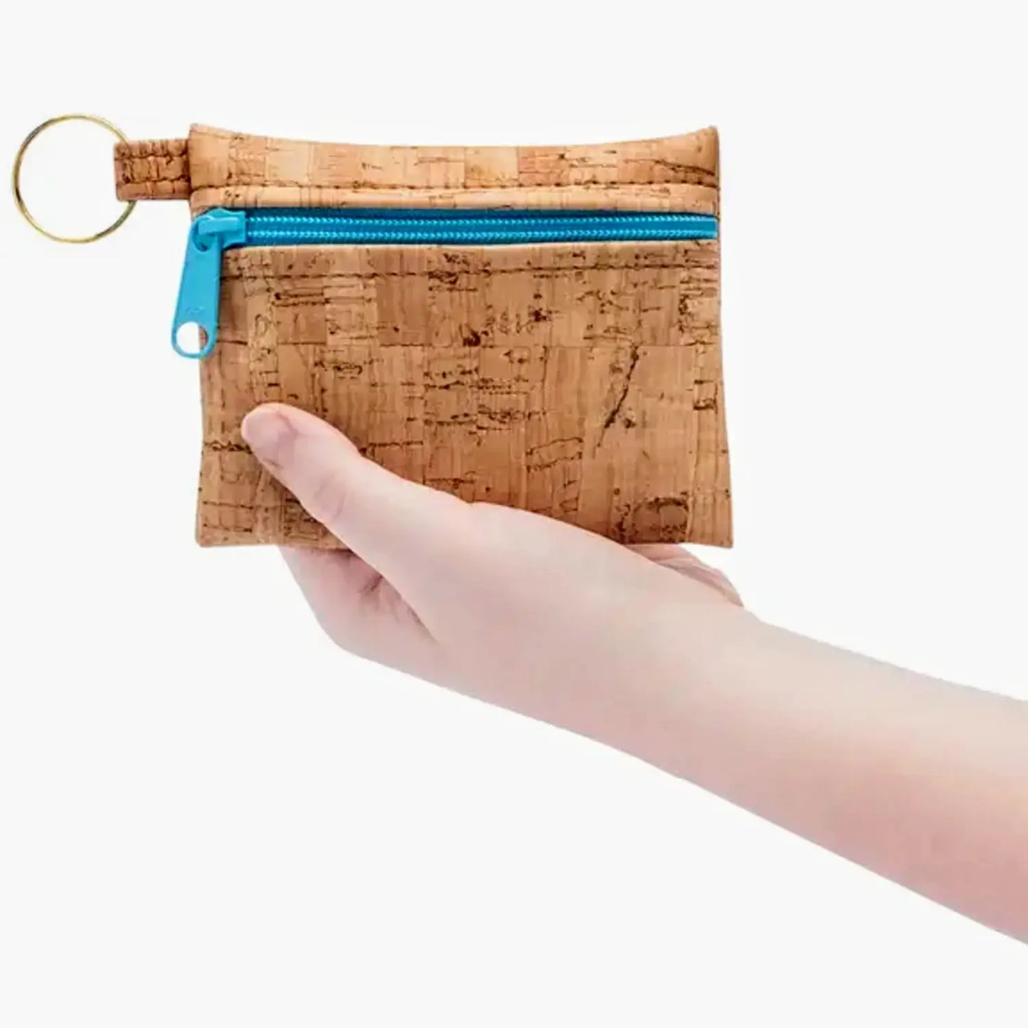 Cork keychain pouch with blue zipper held by a hand on a white background