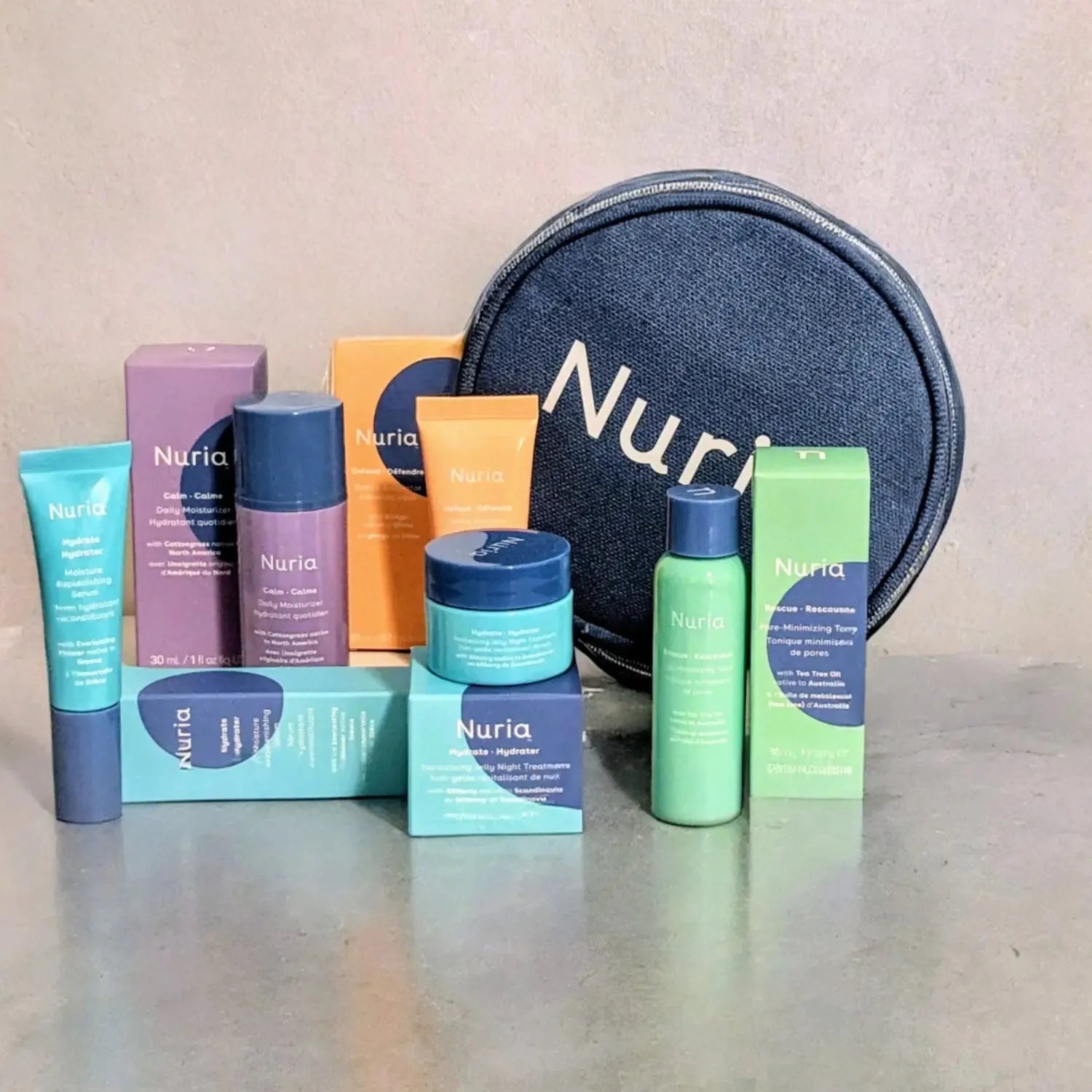 Nuria skincare set with travel size products including bottles, boxes, and a round pouch on a neutral background