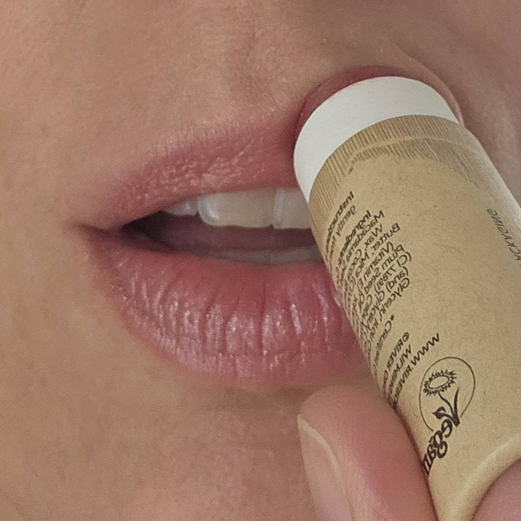 Close-up of a person applying a lip balm stick to their lips.