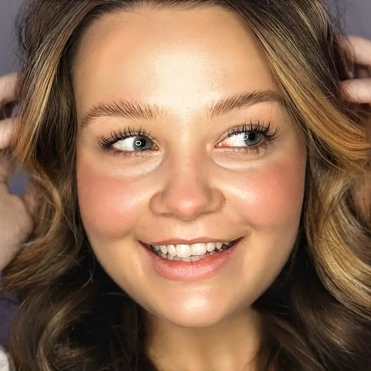 Model wearing Pinch Pink Organic Blush Stick with a radiant, natural glow. Cream blush enhances cheeks with a soft, healthy flush.