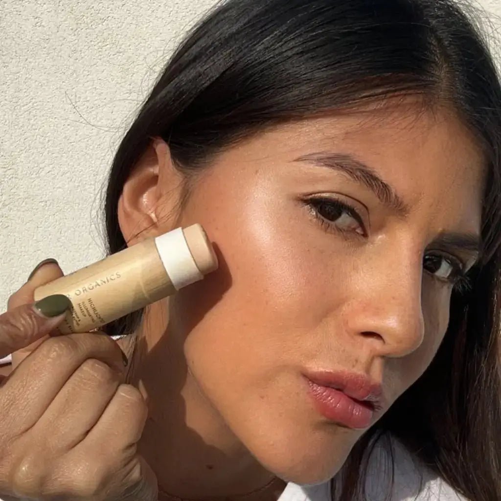 woman applying river organics vegan highlighter stick in a zero-waste paper tube o face and cheeks