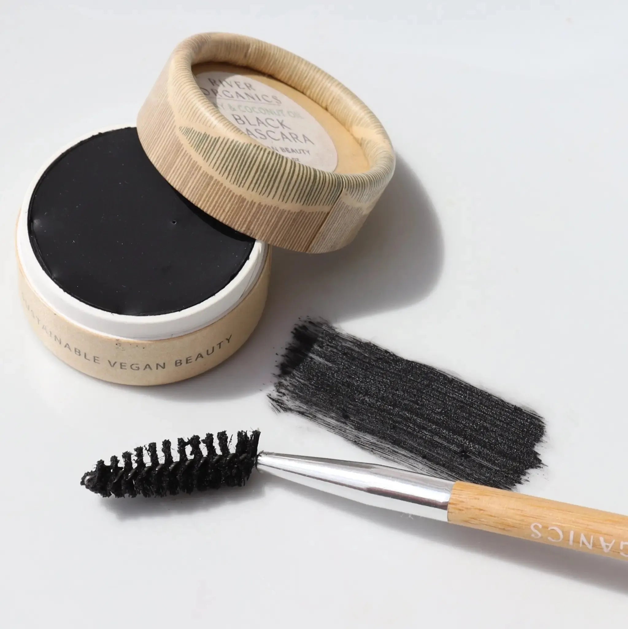 Black Cake mascara product in a container with a brush on a light background