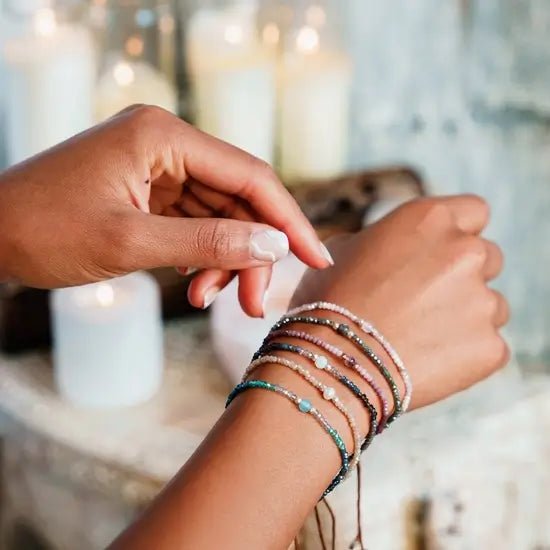 a wrist wearing lotus and luna bracelets, colorful intention bracelets featuring crystals and healing energy gemstones.