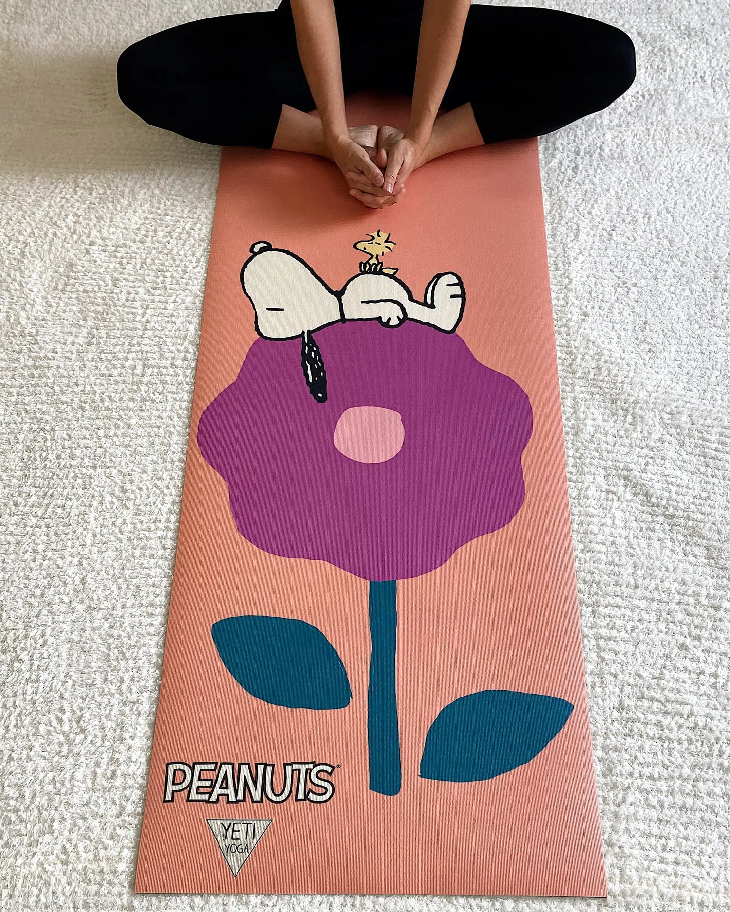 a person sitting on a yoga mat with a flower painted on it
