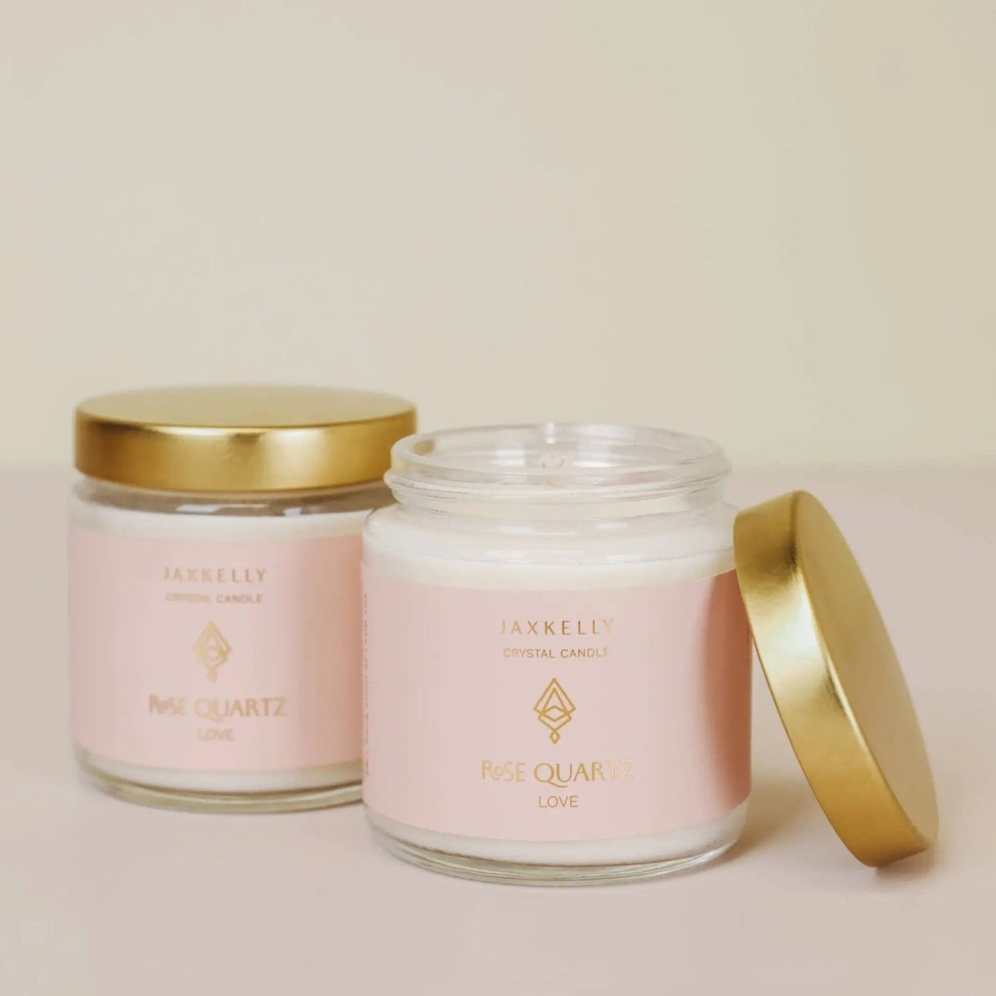 two vanilla candle jars with pink quartz inside with gold lids