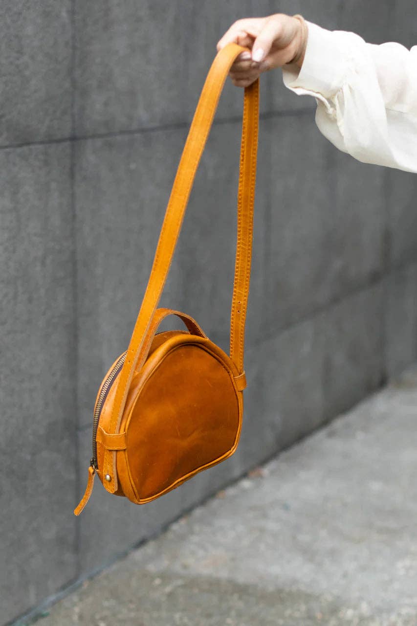 a person holding a brown purse on an adjustable shoulder strap
