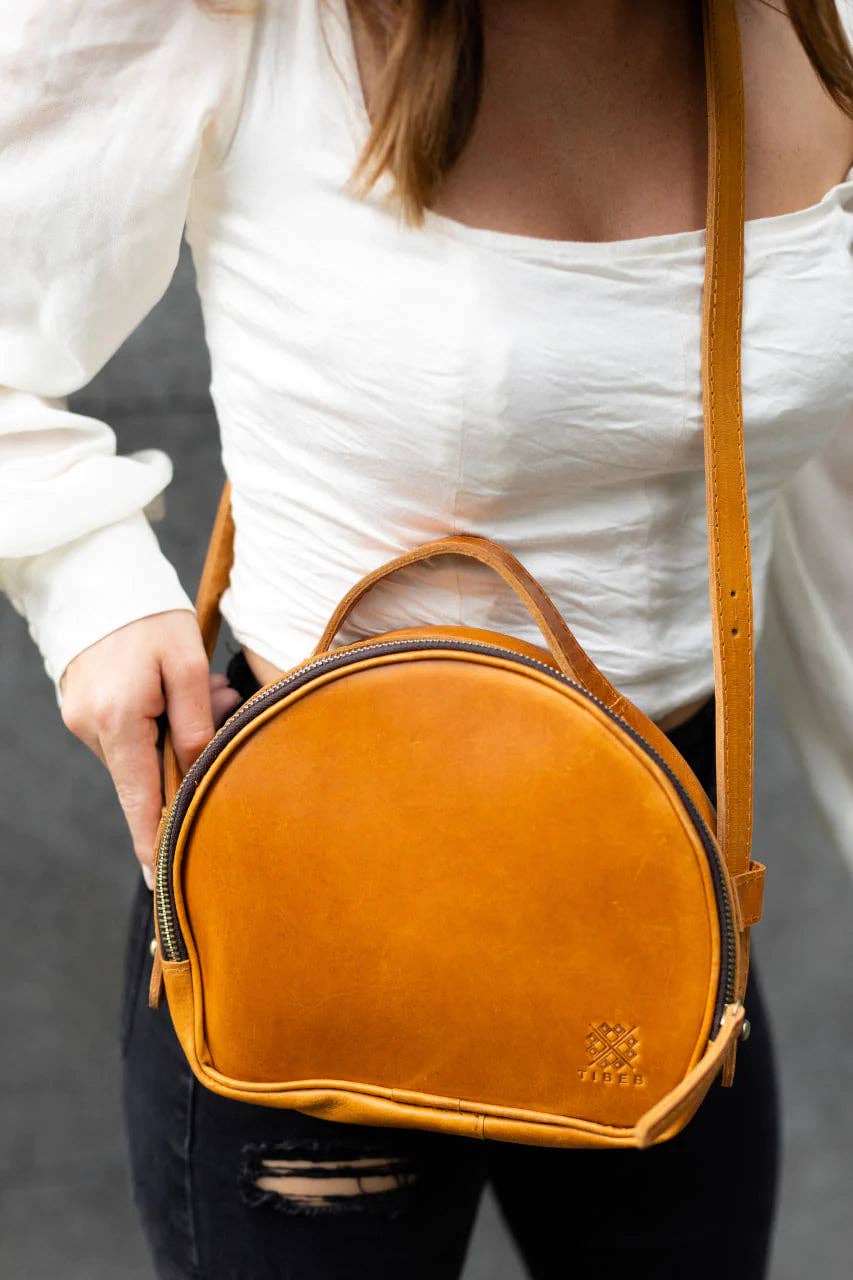 a woman wearing a white shirt and black jeans holding a brown leather purse