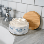 A Jar of The Organic Skin Co Dream Cream Anti-aging Facial Moisturizer on a Bathroom Countertop.