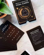 Yoga practice cards on a marble surface with a plant in the corner.