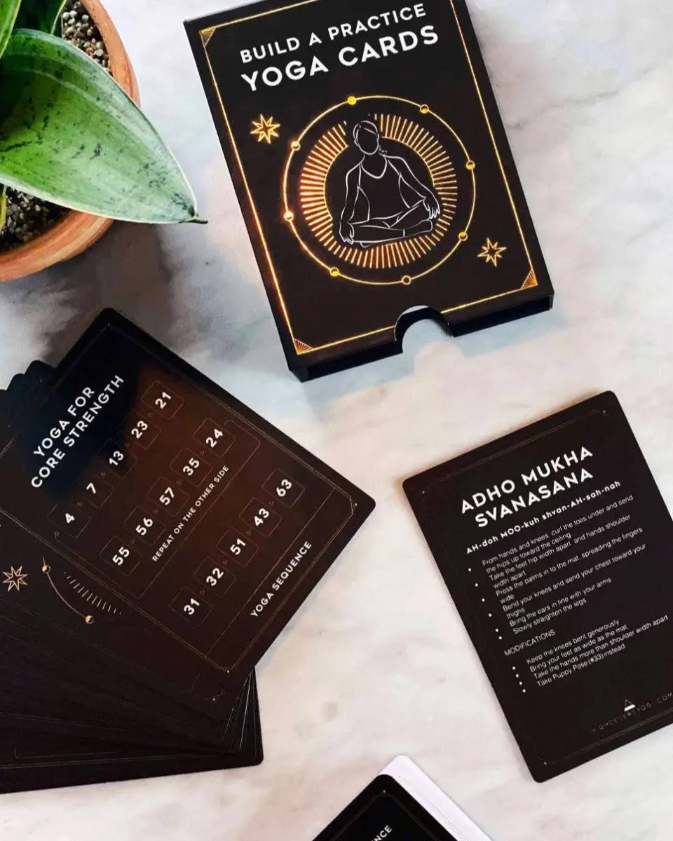 Yoga practice cards on a marble surface with a plant in the corner.