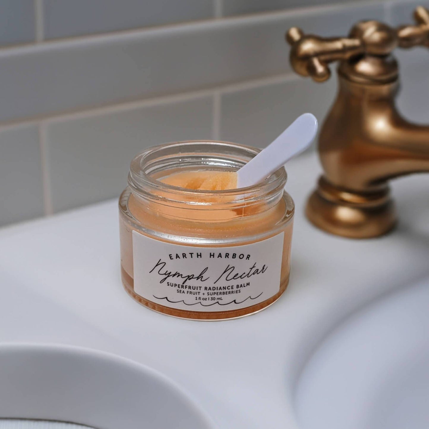 a jar of earth harbor nymph nectar with a spatula sitting on a bathroom counter