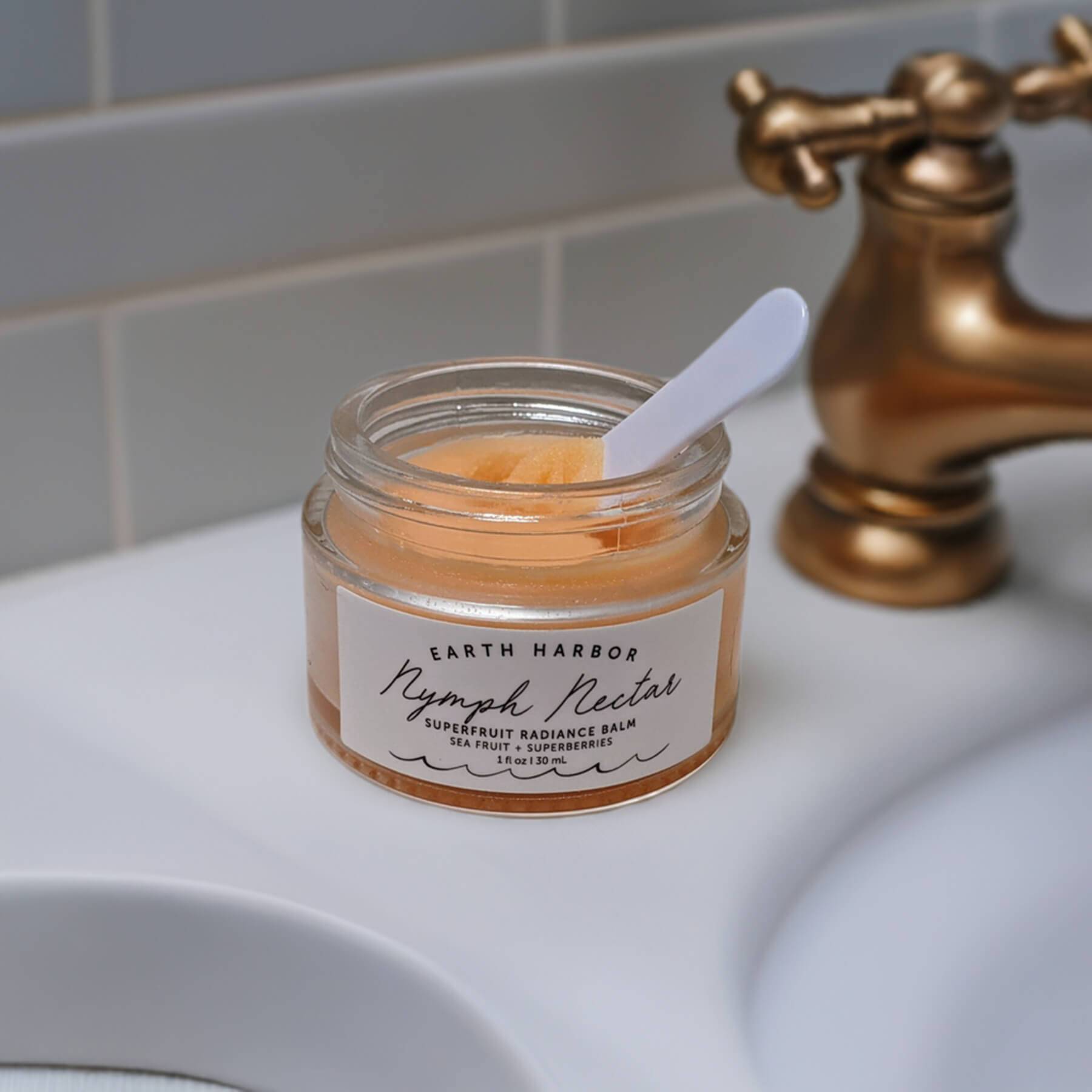 a jar of earth harbor nymph nectar with a spatula sitting on a bathroom counter