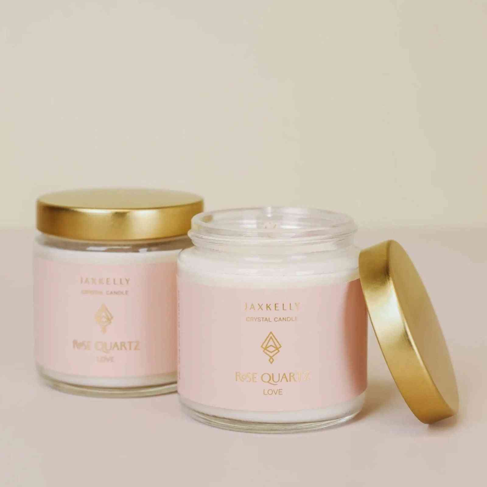 two vanilla candle jars with pink quartz inside with gold lids
