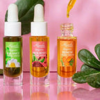Close-up of Kuumba Made Botanical Facial Serum Discovery Gift Set featuring three organic serums on pink background with dropper in use.