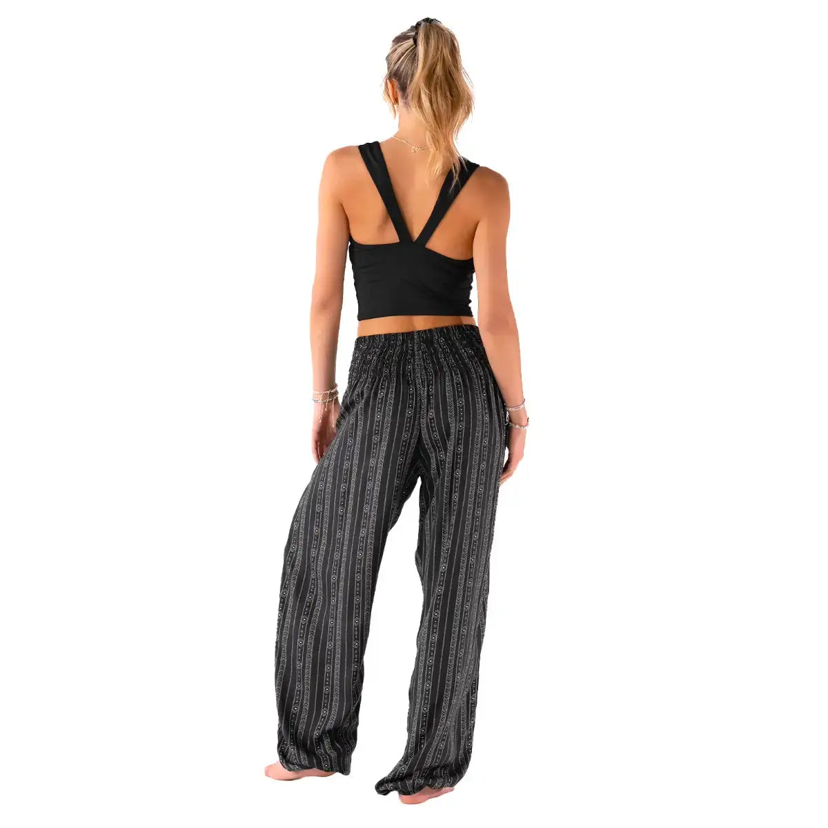 Back view of Striped Black Boho Harem Pants with Pockets by Lotus and Luna, featuring elastic cuffs and tribal stripe design.