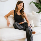 Model lounging in Striped Black Boho Harem Pants with Pockets by Lotus and Luna, styled for a relaxed indoor look.