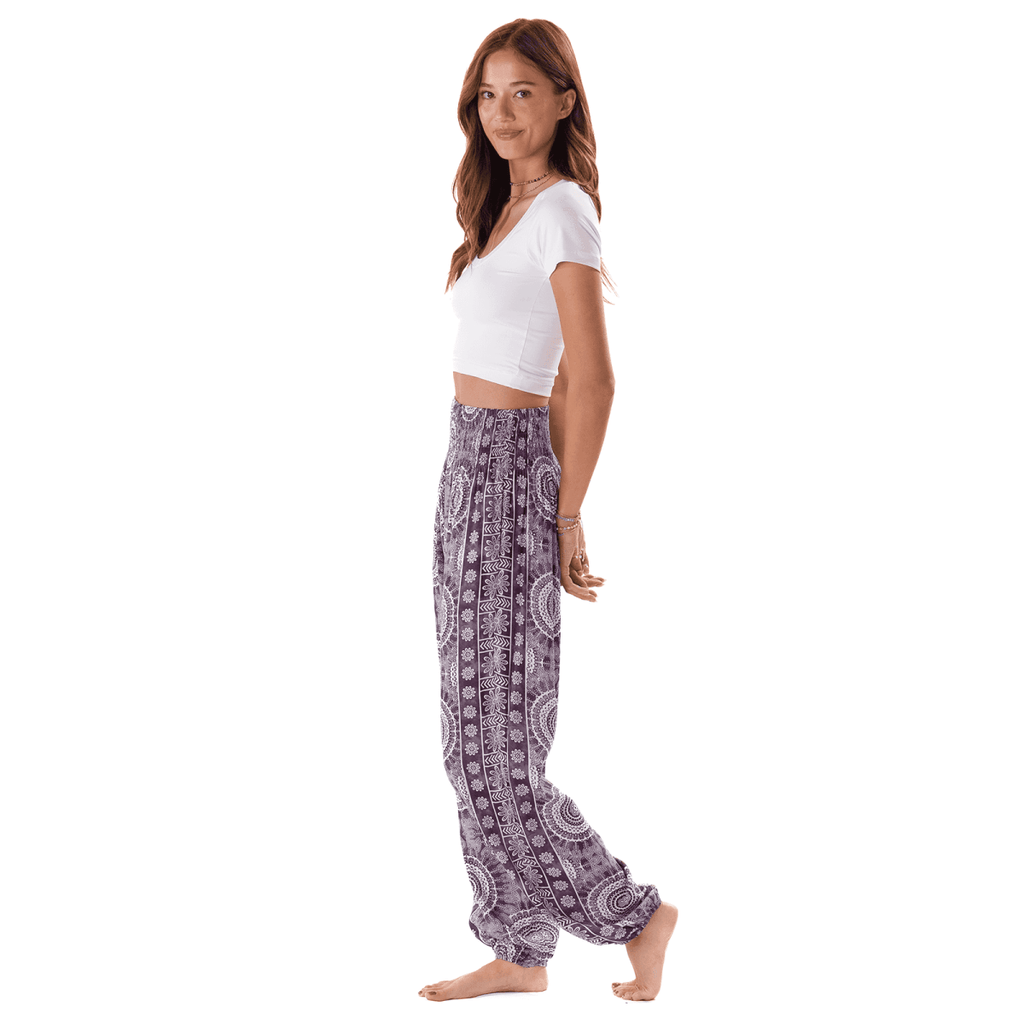 Woman wearing Lotus and Luna Madeira Harem Pants with Pockets featuring a purple mandala print and smocked waistband.