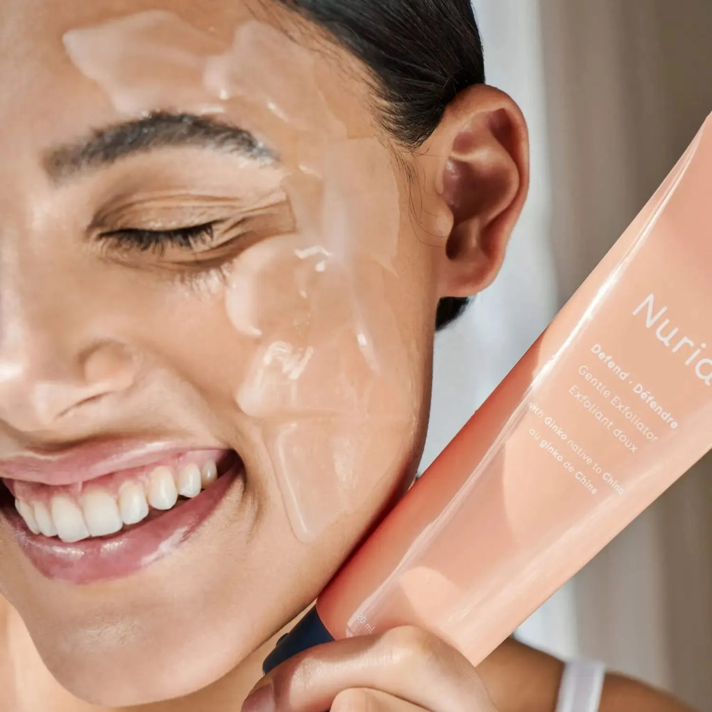 Woman applying a skincare product to her face with a visible nuria brand name.