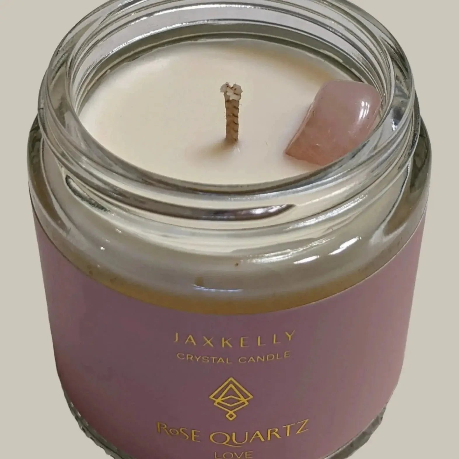 a candle with a small piece of pink quartz in it