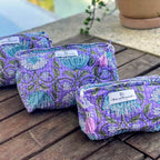 a set of three purple floral toiletry and cosmetics bags with zippers and decorative tassel pulls