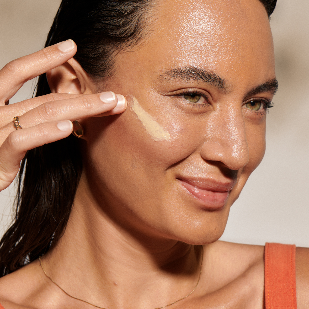 Woman applying Smoothing Face Primer with SPF 30 by Minori, a clean mineral sunscreen that smooths pores and preps skin for makeup.