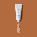 Minori Smoothing Face Primer with SPF 30 in a white tube, shown with creamy mineral sunscreen swatch on a brown background.