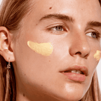 A woman with The Organic Skin Co. Task Force Nine Aloe Calming Cream applied to her cheeks.