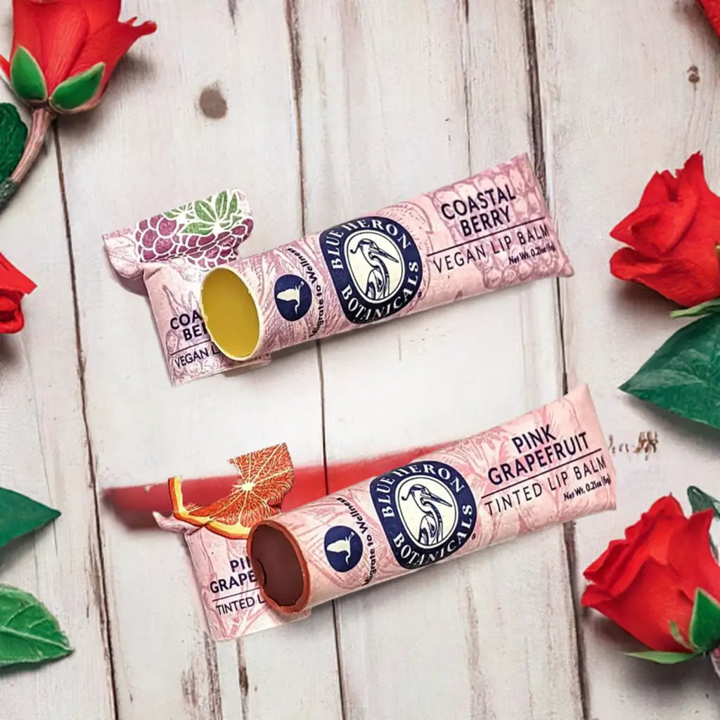 vegan organic clear lip balm and organic red tinted lip balm duo for in zero waste paper tubes next to roses for a valentine's day gift