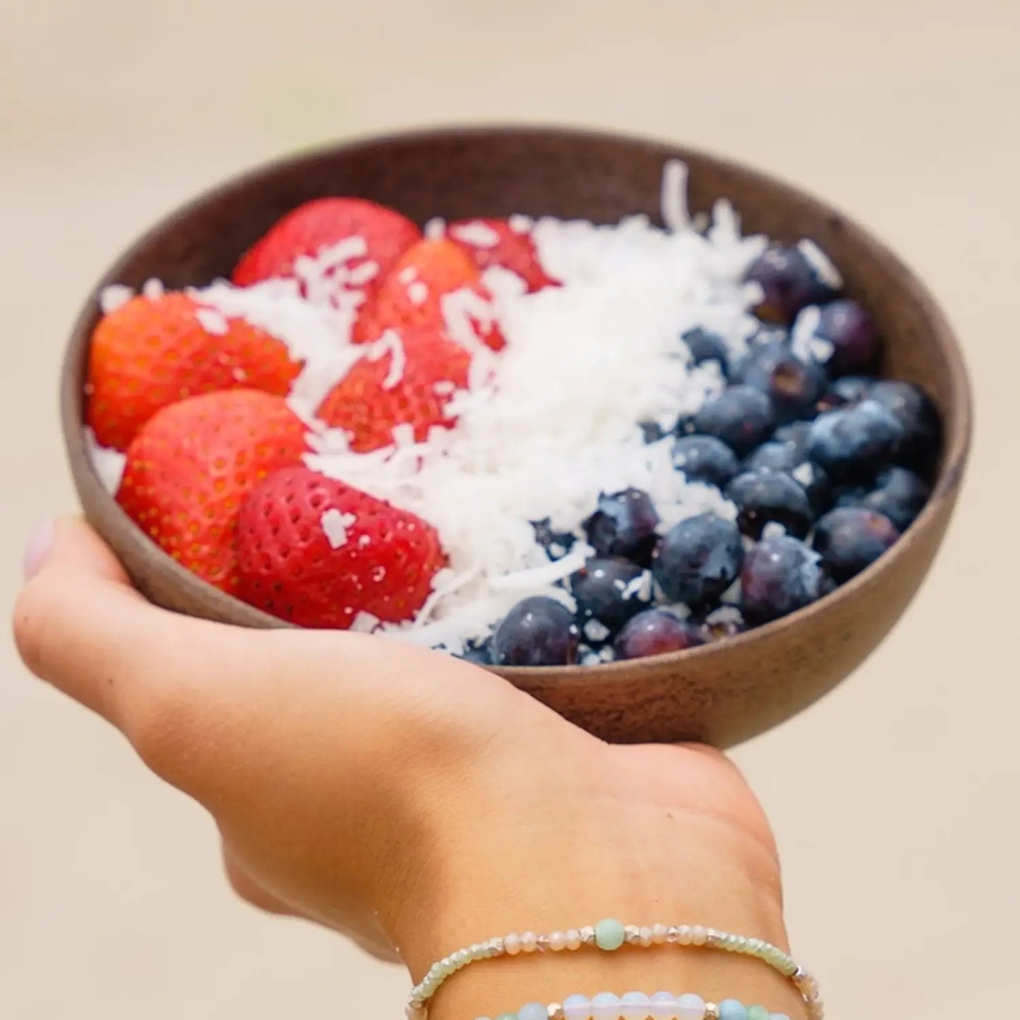 woman's hand holding a bowl of berries wearing a green Amazonite bracelet on wrist
