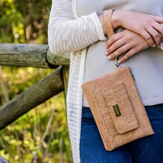 model holding the bent and bree leia natural cork clutch wallet with the detachable strap on her wrist
