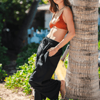 black wide leg pants with pockets and drawstring high-rise waist on model leaning against a palm tree
