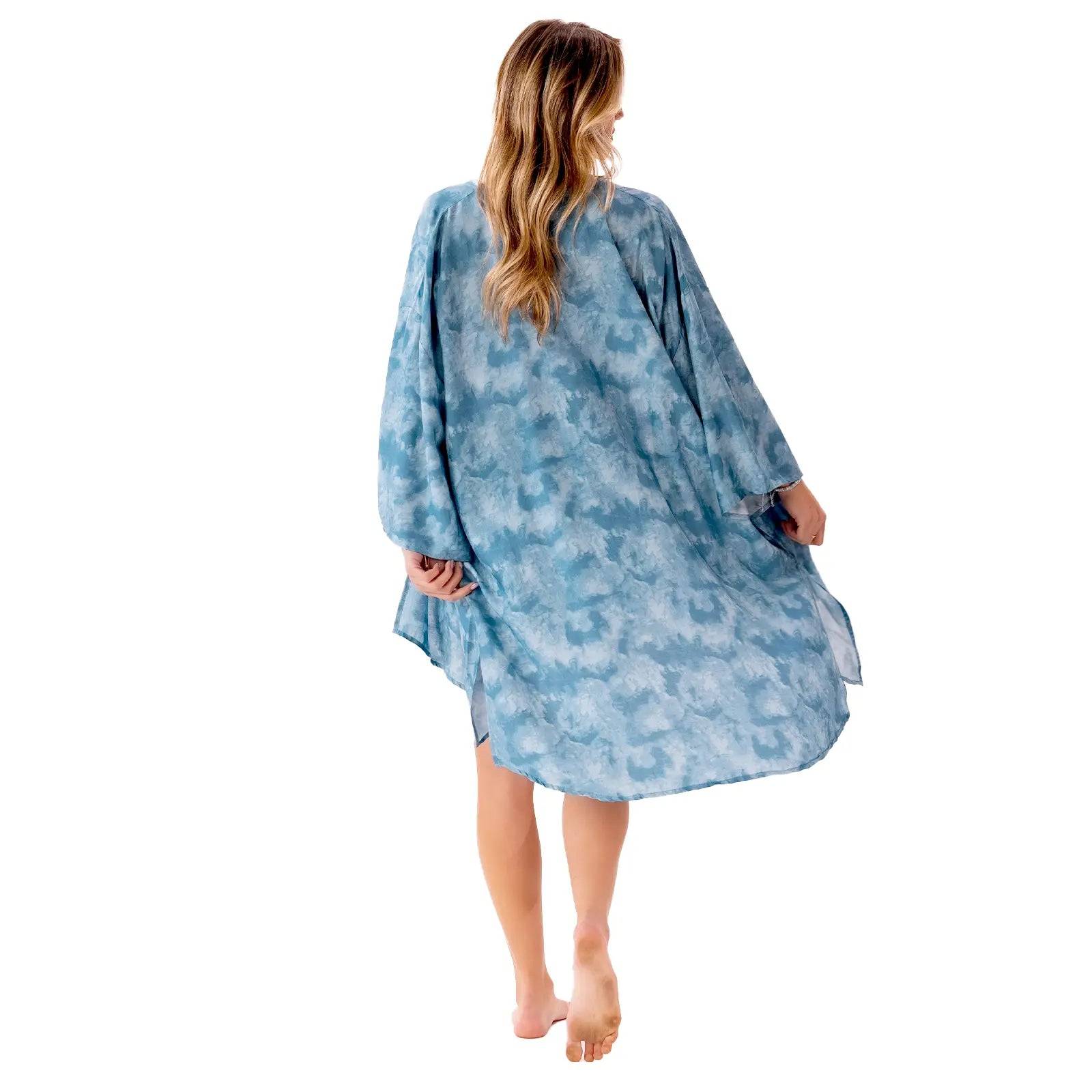 a woman in a blue swim cover up walking away from the camera