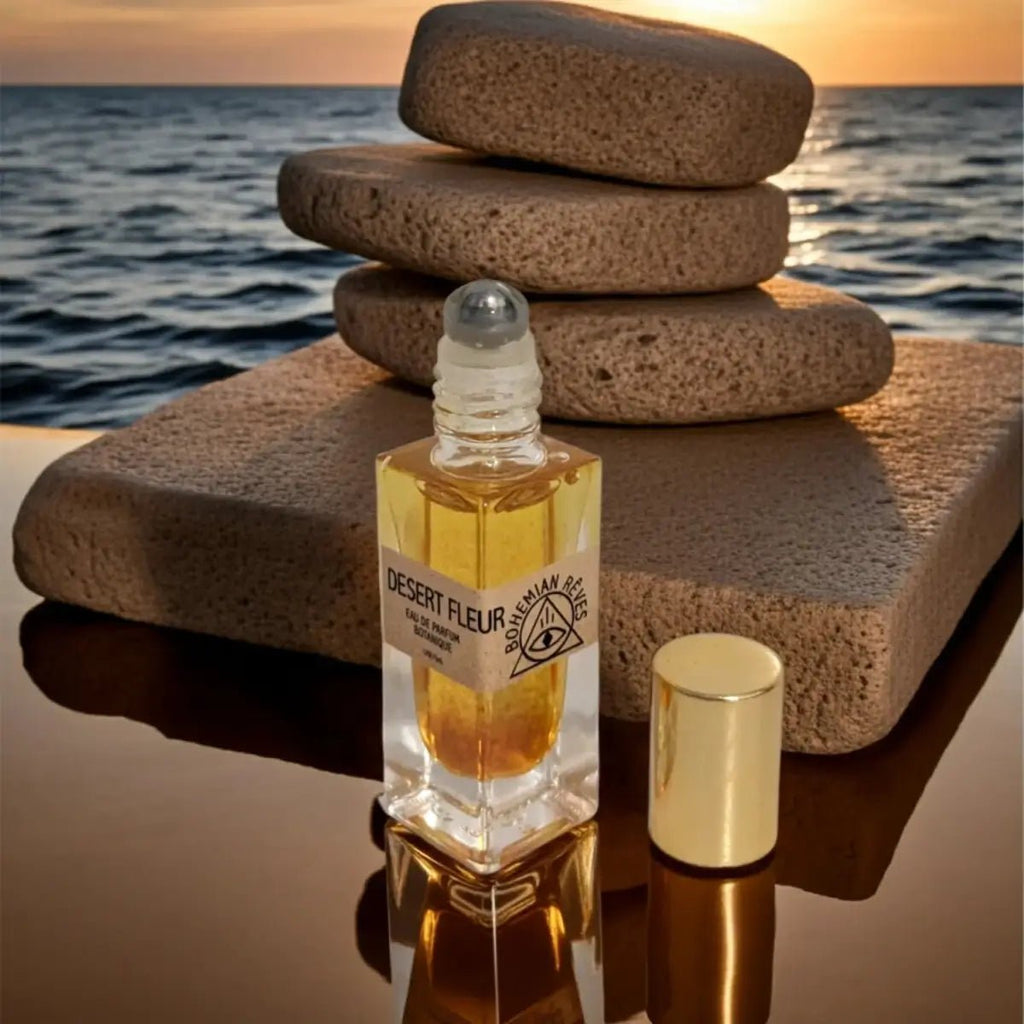 Desert Fleur perfume bottle on a rock with ocean and sunset background