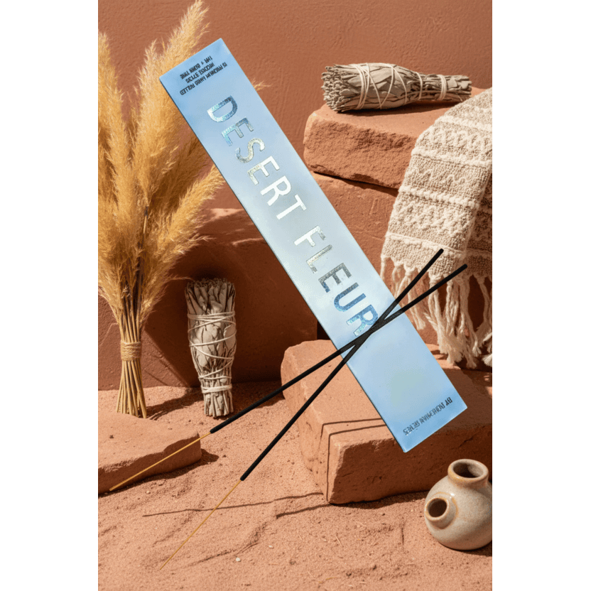 Bohemian Rêves  Desert Fleur Perfume Incense Sticks laying amongst dried pampas grass, small white sage bundles, a woven textile, and a small ceramic pot in a warm earthy styled setting.