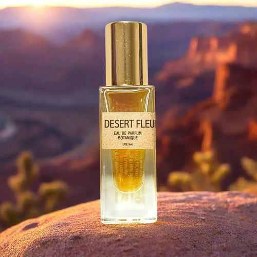 A bottle of Bohemian Reves Desert Fleur Perfume sitting on a canyon rock against the background of an Arizona desert sunset.