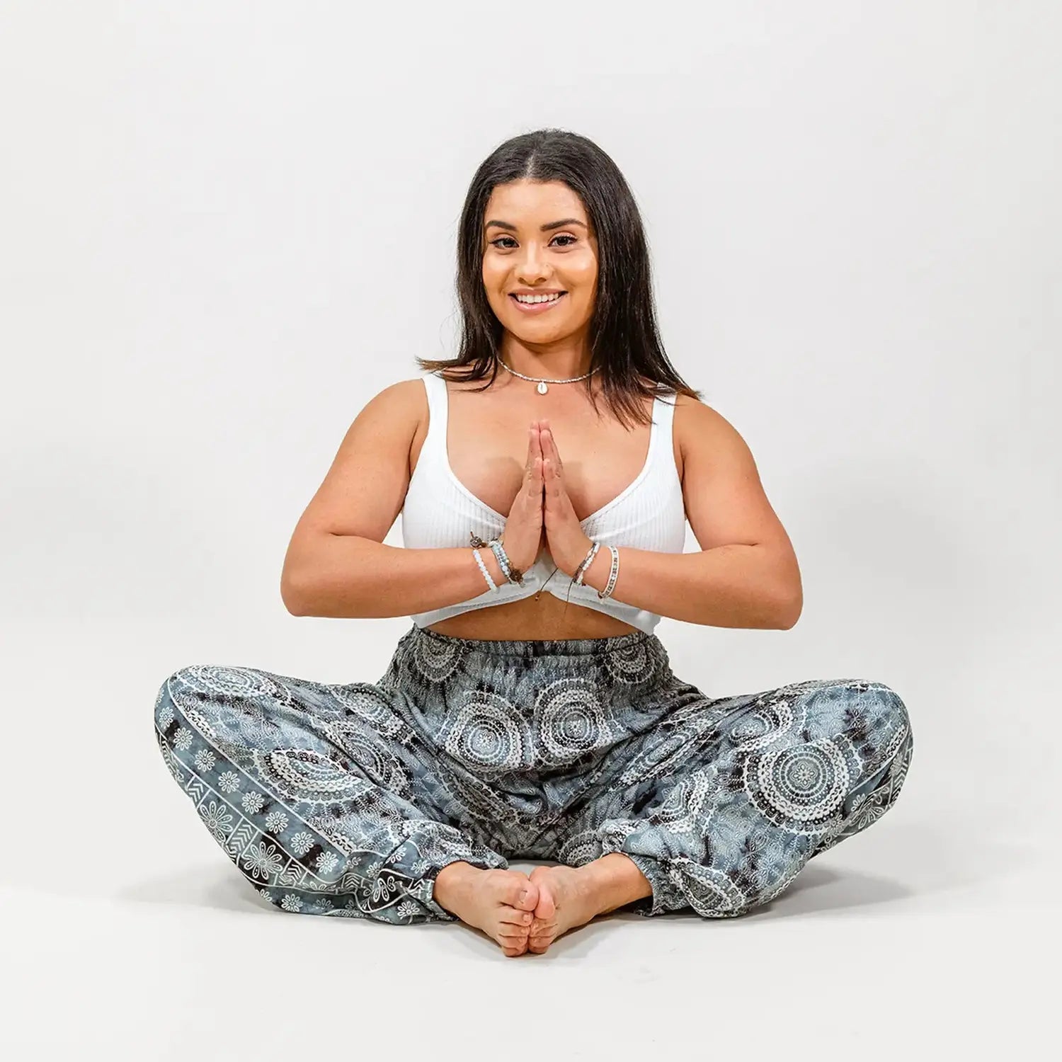 Woman in blue boho harem lounge pants with hands in Namaste