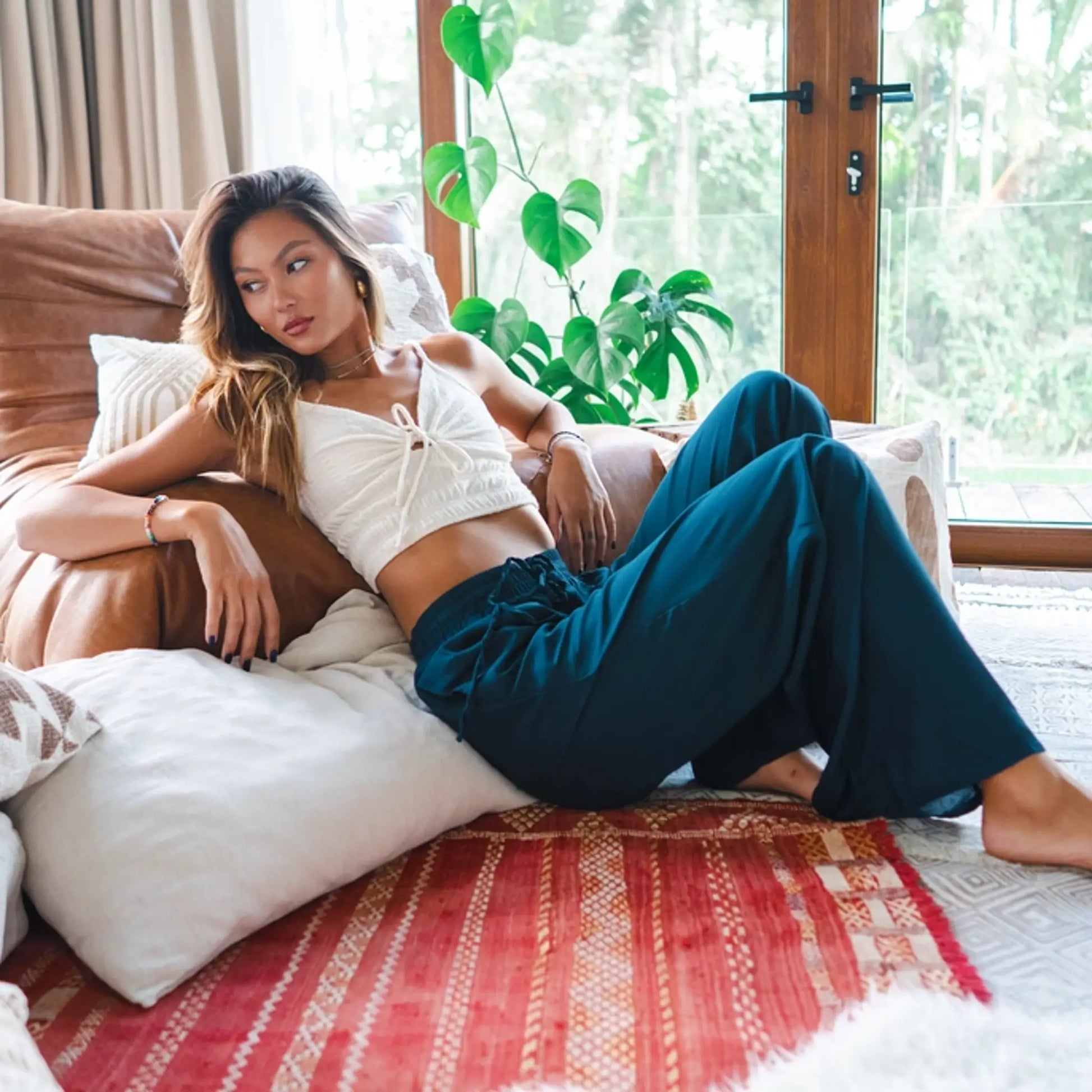 woman relaxing in a pair of teal colored boho wide leg pants from lotus and luna